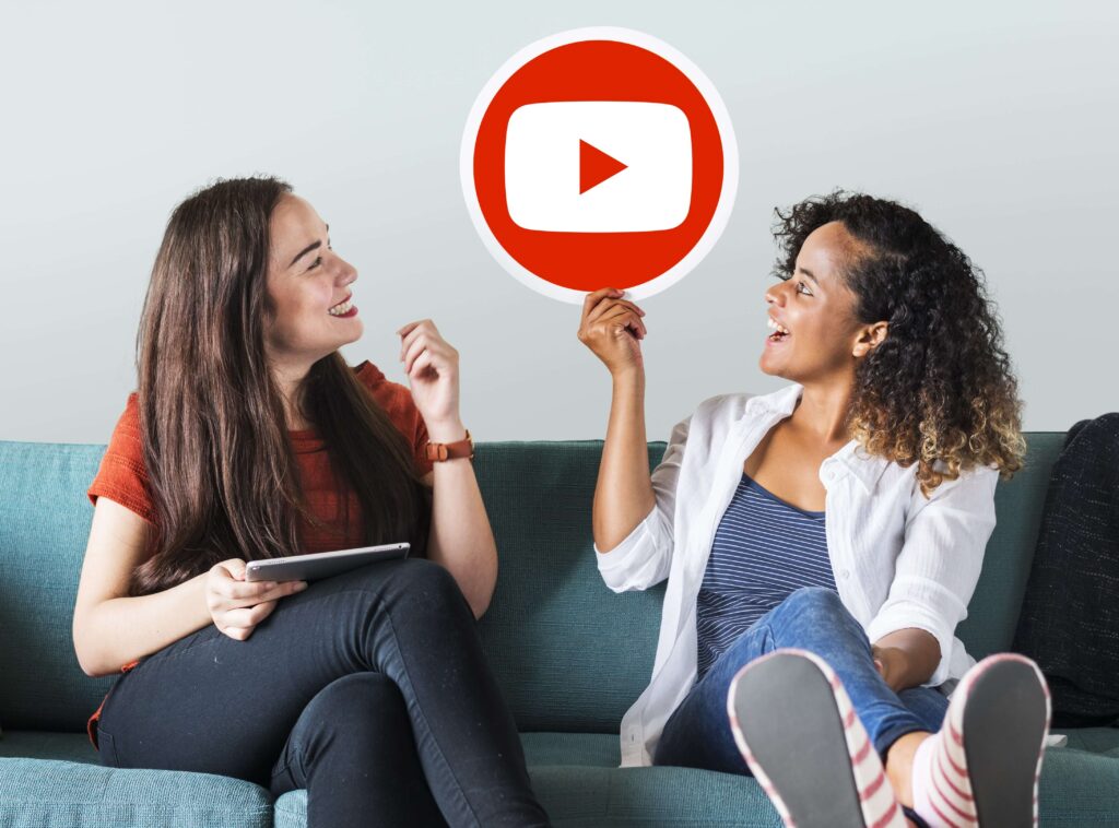 Female French youtubers holding the Youtube logo and smiling