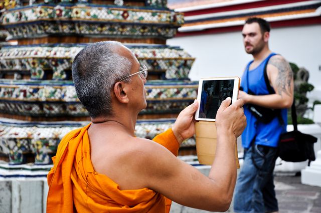 Buddhist monk using a tablet at a Thai temple,