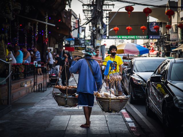 Street vendor walking through a busy market in Thailand